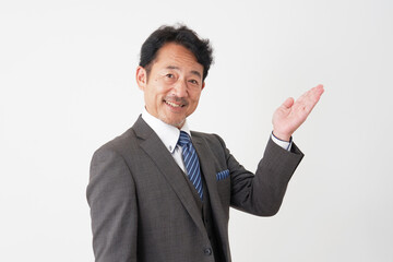 右側を手のひらで指すミドルエイジのビジネスマン　白背景