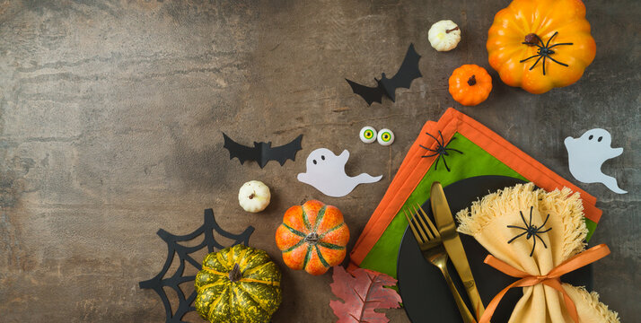 Halloween party banner concept with  plate, pumpkin and decorations on dark background. Top view, flat lay