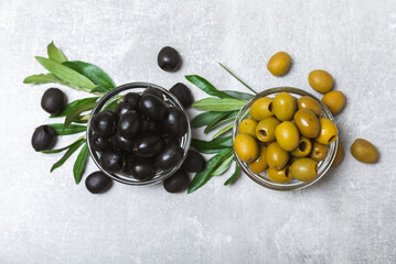 Black and green olives on a light marble background. Fresh juicy olives in a bowl and fresh olive...