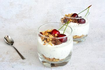 snack in glass with muesli, yogurt, chia seeds and cherry copy space  
