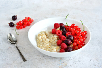 bowl with oatmeal and fresh raspberry, gooseberry and red currant copy space  