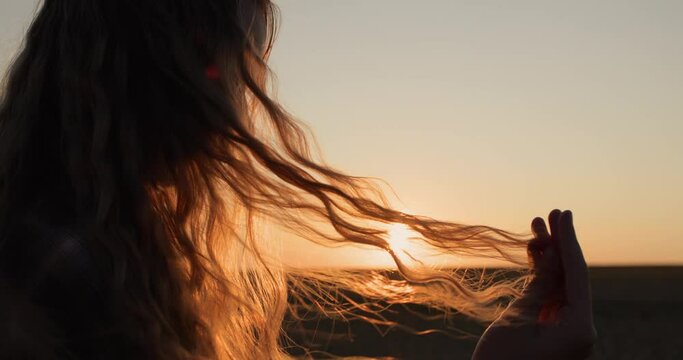 Teen looks at her hair in the sun, holds a lock of hair in her hand