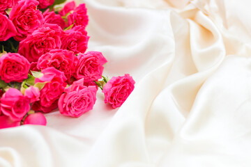 Small pink bush roses on a white silk background with a place for text
