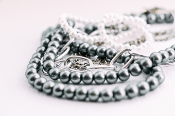 A necklace of gray beads with chain decorations on a white aesthetic background.