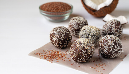 Healthy raw energy balls with cocoa, coconut, sesame, chia on a white background. Vegan chocolate truffles. Copy space. Selective focus. Horizontal.