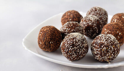 Healthy raw energy balls with cocoa, coconut, sesame, chia on a white background. Vegan chocolate truffles. Copy space. Selective focus. Horizontal.