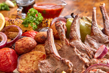 Part of the wooden board with fried meat and vegetables on the wooden table,close-up, shallow depth of field. Lamb meat and vegetables in focus