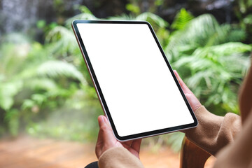 Fototapeta na wymiar Mockup image of a woman holding digital tablet with blank white desktop screen in the garden