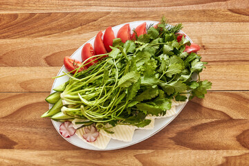 White plate with greens, tomatoes, curd cheese and radishes on the wooden table. Top view, flat lay