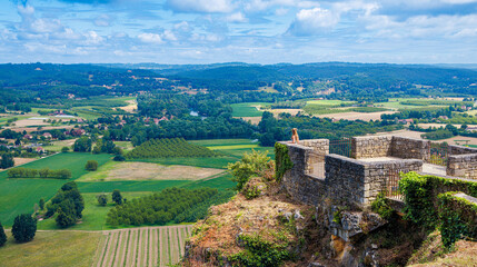 Naklejka premium Beautiful panoramic landscape with field and meadow view with woman enjoying at the viewpoint- travel, tour tourism in France- Dordogne, Perigord