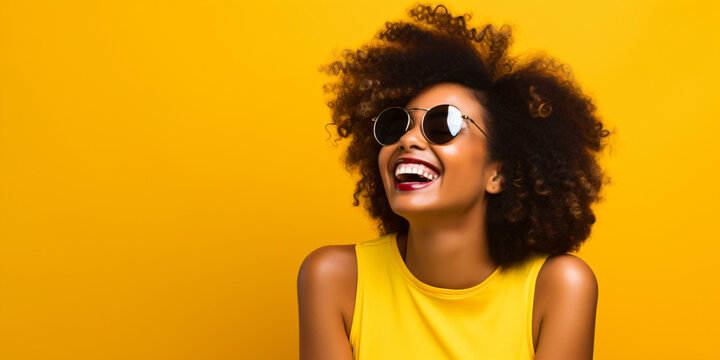 laughing young black woman with cool sunglasses isolated on a yellow background wall