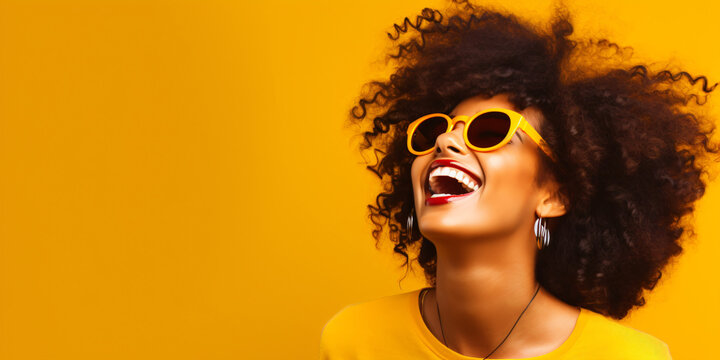 laughing young black woman with cool sunglasses isolated on a yellow background wall