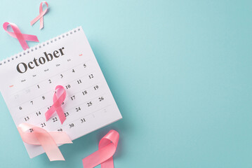 Breast cancer awareness campaign essentials. Top view shot of October calendar, and pink ribbons on pastel blue backdrop. Optimal for medical marketing