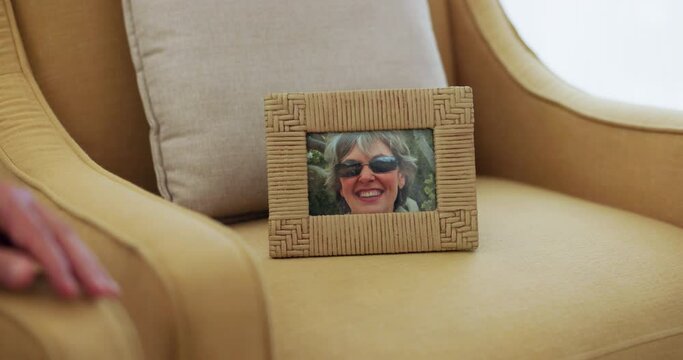 Grief, loss and photograph of memory in house, chair of deceased woman, wife or mother in living room or nursing home. Photo, frame or picture of lady on sofa or couch to honor death of person