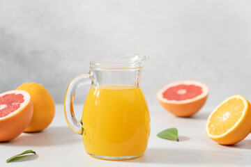 Orange juice in jur surrounded by citrus fruits. Detox, vitamin cocktail in bottles