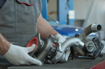 A new turbine and a faulty turbine are on the car mechanic's desktop. Replacement of a turbine in...