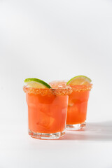Grapefruit tropical cocktail with lime and ice on white background. Refreshing summer drinks