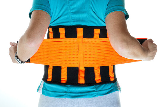 Back woman putting on a lumbar girdle to take weight and relieve pain. High quality photo