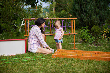 mom with little daughter collects home sports complex outdoor.