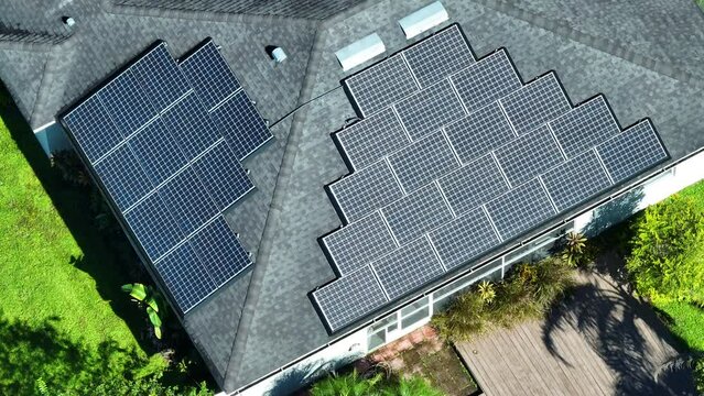 Ordinary residential house in USA with rooftop covered with solar photovoltaic panels for producing of clean ecological electrical energy in suburban rural area. Concept of autonomous home