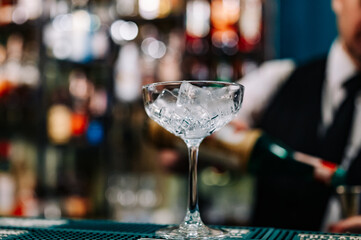 Ice cube in an empty glass on a bar counter in bar or pub