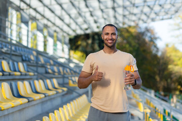 Portrait of sportsman with bottle of water, man resting walking stadium for training, young athlete yoga and fitness trainer