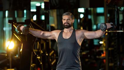 Caucasian beard muscular sport man is practice weight training on double dumbbells for biceps and...