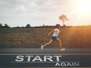 Start again.  Young Asian woman running forward in the evening. on the road with a message start...