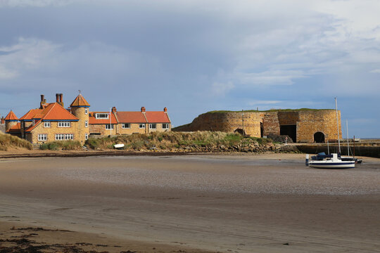 The ancient castle and other buildings at the end of Beadnell beach in Northumberland, England, UK.