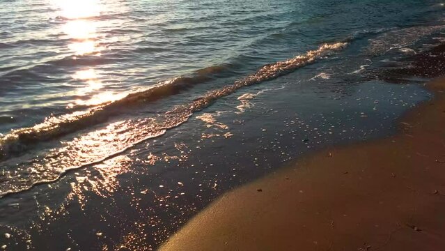 Water lapping over sandy beach shore at sunset