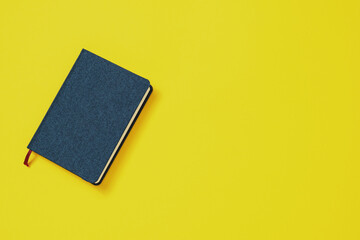 Education or Business Style Concept. Closed blue notebook with a nice cover on a yellow background