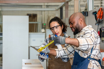 Two colleague young aged carpenter standing aim equipment tool for wood furniture at wood plank in workshop. coworker carpenter working craft with wood diy tool in workbench shop carpentry