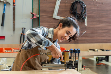 One Strong confident young aged women carpenter standing aim at wood plank in workshop. Latin...