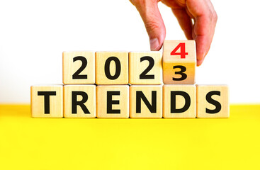 2024 trends new year symbol. Businessman turns a wooden cube and changes words Trends 2023 to Trends 2024. Beautiful white table white background, copy space. Business 2024 trends new year concept.