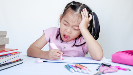 Portrait Of Sleepy Little Asian Female Child At Desk Tired After Doing School Homework.