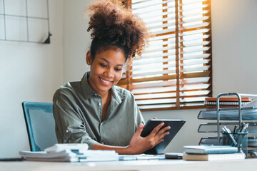 African American teenage woman using a digital tablet and Laptop. Young leading businesswoman using a wireless tablet. Creative designer working in her House