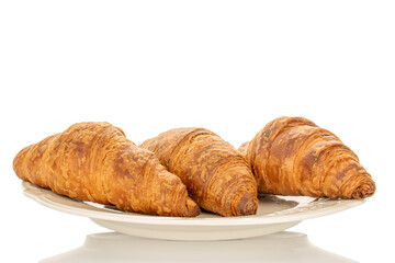 Three fragrant croissants with chocolate filling on a white ceramic plate, close-up, isolated on white.