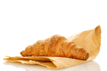 One fragrant croissant with chocolate filling on a bag of craft paper, close-up, isolated on white.