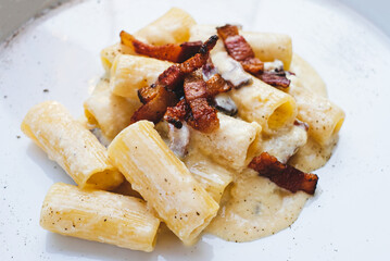 Rigatoni alla carbonara, italian pasta dish with eggs, hard cheese, cured pork, and black pepper.