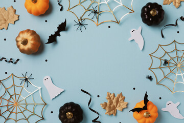 Halloween holiday frame with party decorations from pumpkins, bats, spider web and ghosts top view. Happy halloween greeting card on blue background flat lay style.. - 634100683