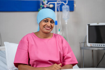 Happy smiling indian recovered breast cancer patient looking camera on bed at hospital - concept of...