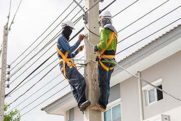 Electricians working on power pole connecting cables