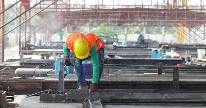 welding. Asian man worker weld metal with a arc welding machine at the construction site. Heavy Industry Manufacturing Factory. Prefabricated concrete walls