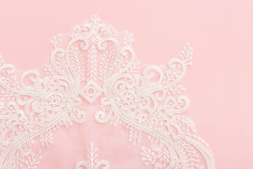 white delicate lace fabric over pink background
