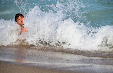 Handsome young man hit by a wave. A handsome young man is having fun in the waves of the sea. 