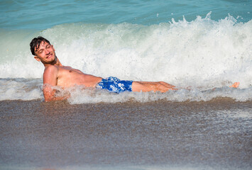 A handsome young man is having fun in the waves of the sea. Single man on vacation.