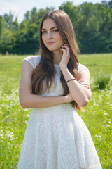 Naklejka na ściany i meble Beautiful girl in a flowery meadow in a white dress in summer
