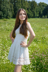 Fototapeta na wymiar Beautiful young smiling woman in a flowery meadow in a white dress