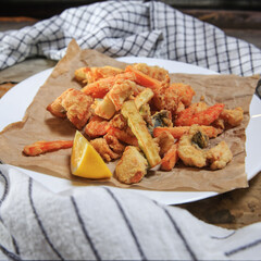 deep fried seafood (fritomisto) on kraft paper on a wooden rustic table with two towels