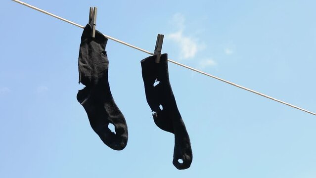 Leaky socks hang on a clothesline against the sky, a concept on the subject of poverty